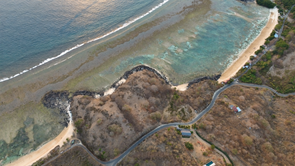 Elevated aerial view across the Glampar Beach headland and shallow coastal waters.