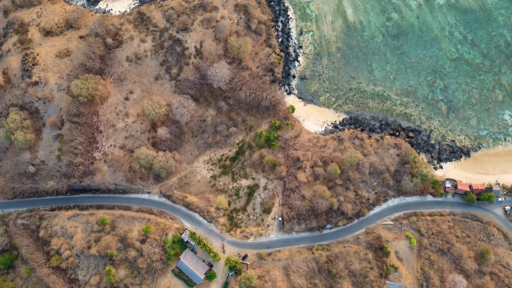 Aerial view of the coastal road beside Glampar Beach and the sea in Kertasari.