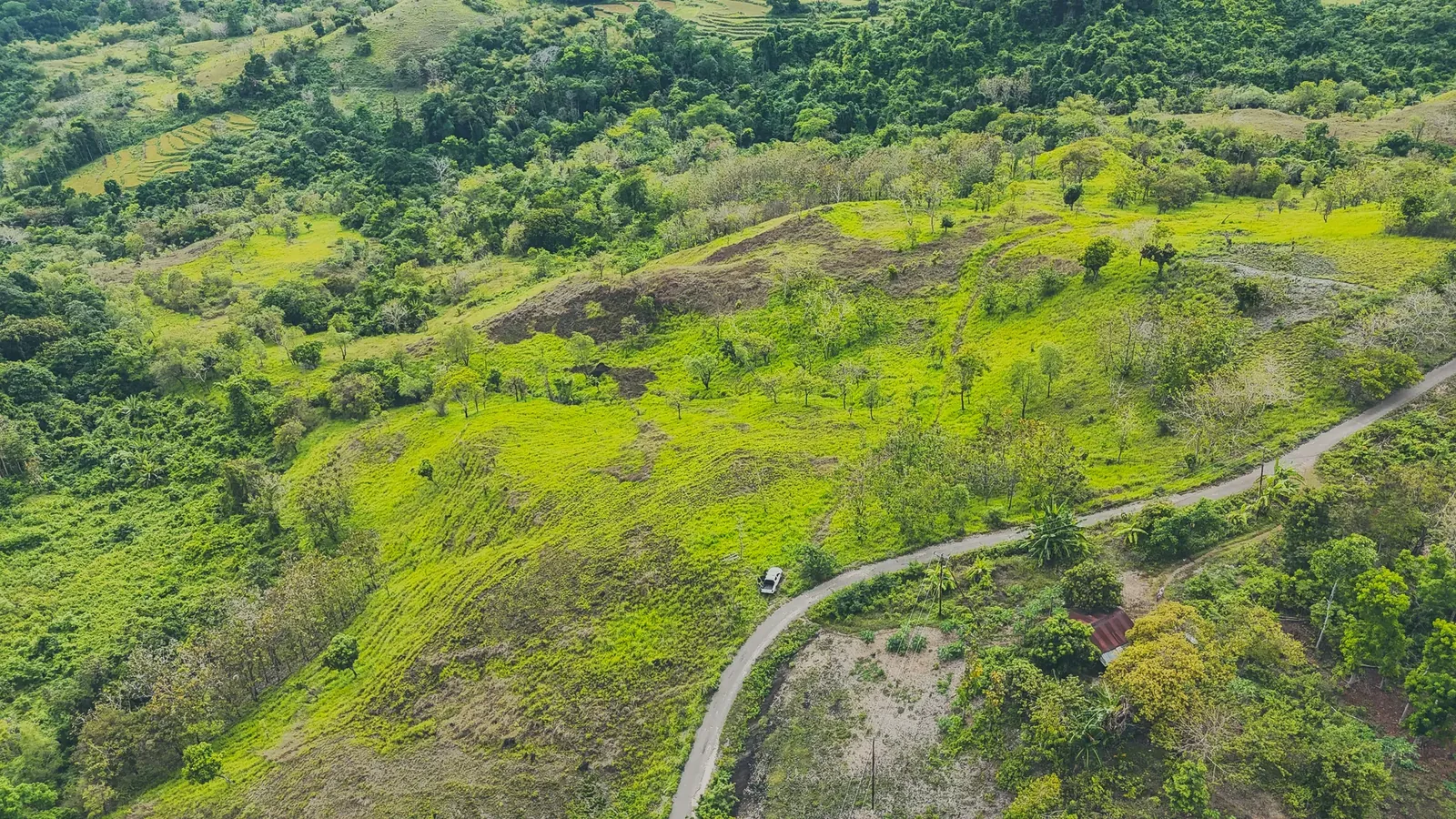 Aerial view of green slopes beside a winding road at Lapopu, Parirara, near Lapopu, West Sumba