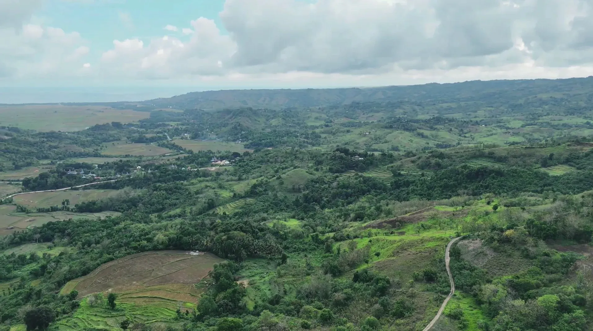 Wide panorama of farmland, wooded hills and cloudy sky at Lapopu, Parirara, near Lapopu, West Sumba